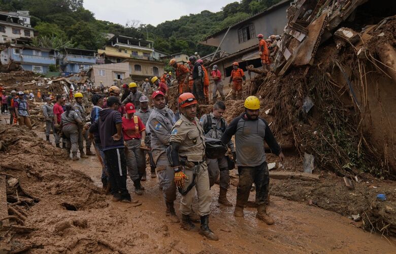 Bombeiros retiram o corpo de vítima dos deslizamentos em Petrópolis (RJ), na sexta-feira (18).