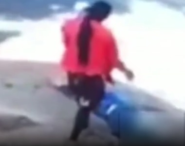 Mulher com criança no colo observa homem caído no chão