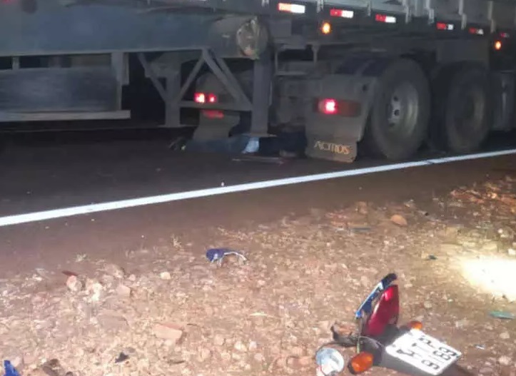 Corpo do motociclista sob a carreta bitrem na rodovia