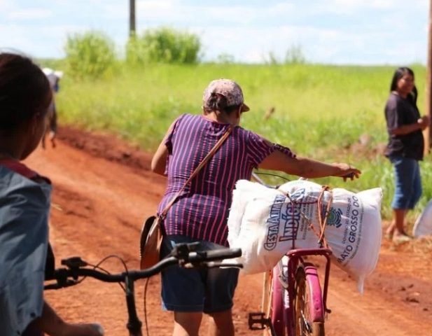 Indígena carrega cesta de alimentos na garupa da bicicleta