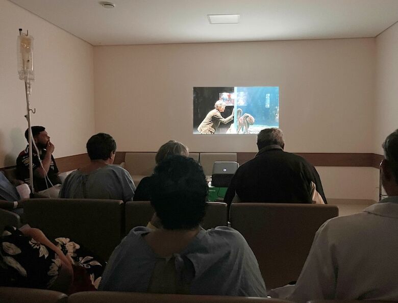 Pacientes oncológicos durante sessão de cinema na Cassems